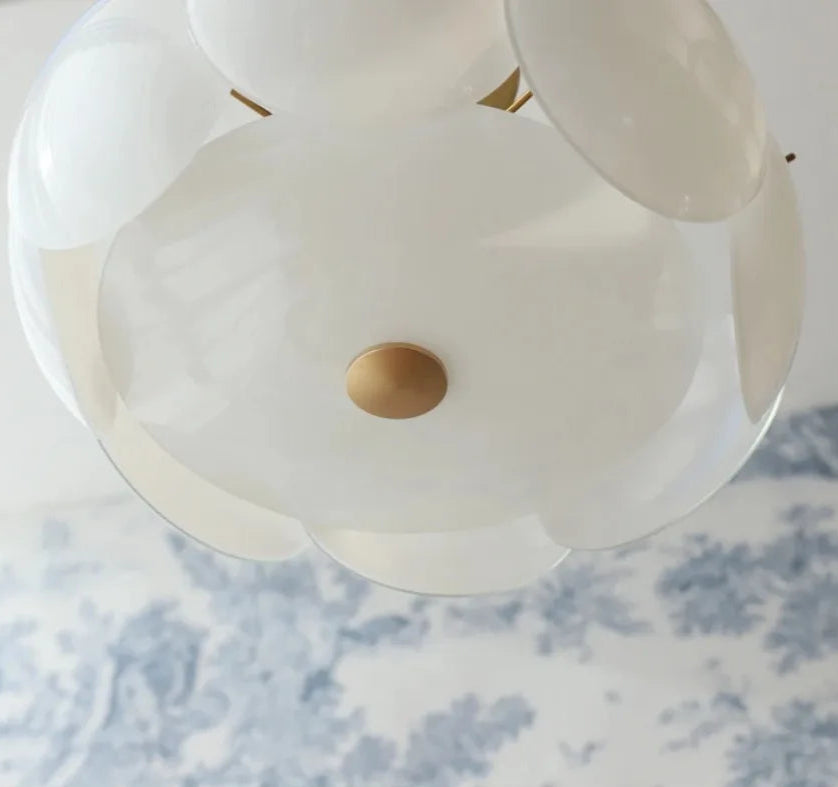 Close-up of a white flower-shaped light fixture with a gold center on a floral-patterned fabric background.