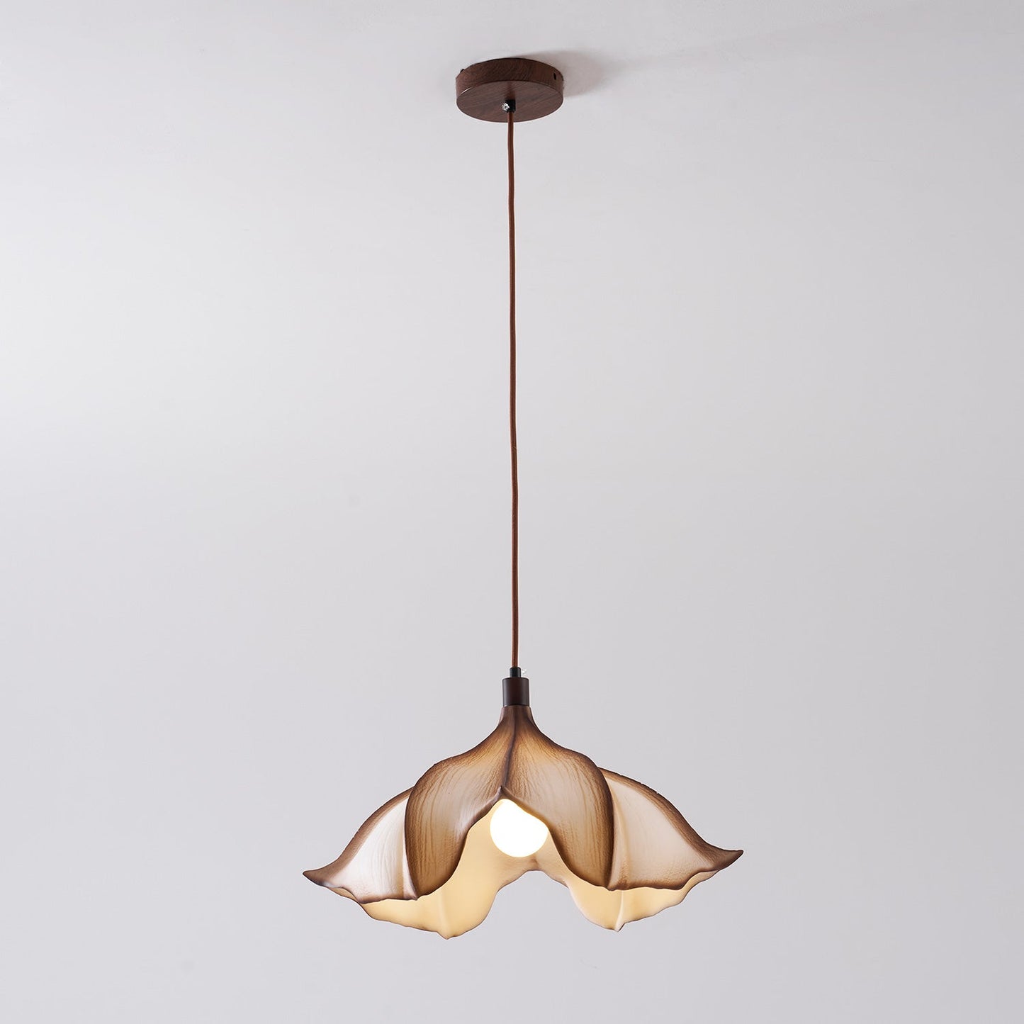 Floral-shaped pendant light with a brown glass shade on a plain background