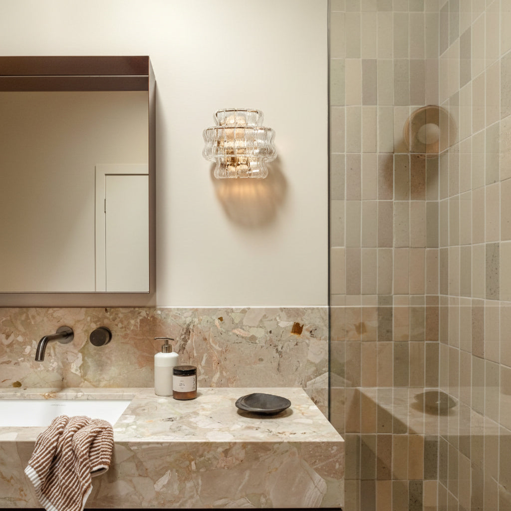 Bathroom interior with marble countertop, mirror, and wall light fixture.