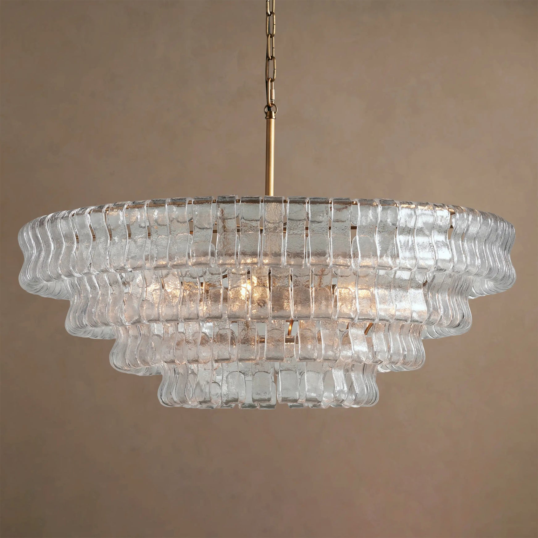 Clear glass chandelier with gold chain on a beige background