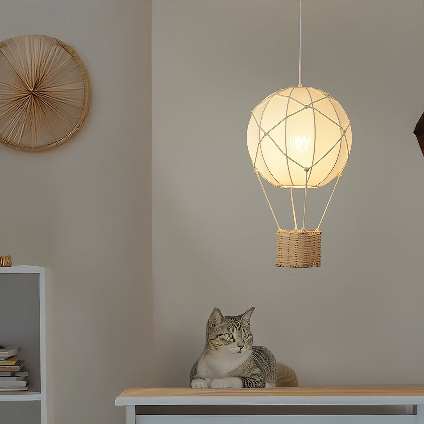 Cat sitting on a table below a unique hanging lamp shaped like a hot air balloon.