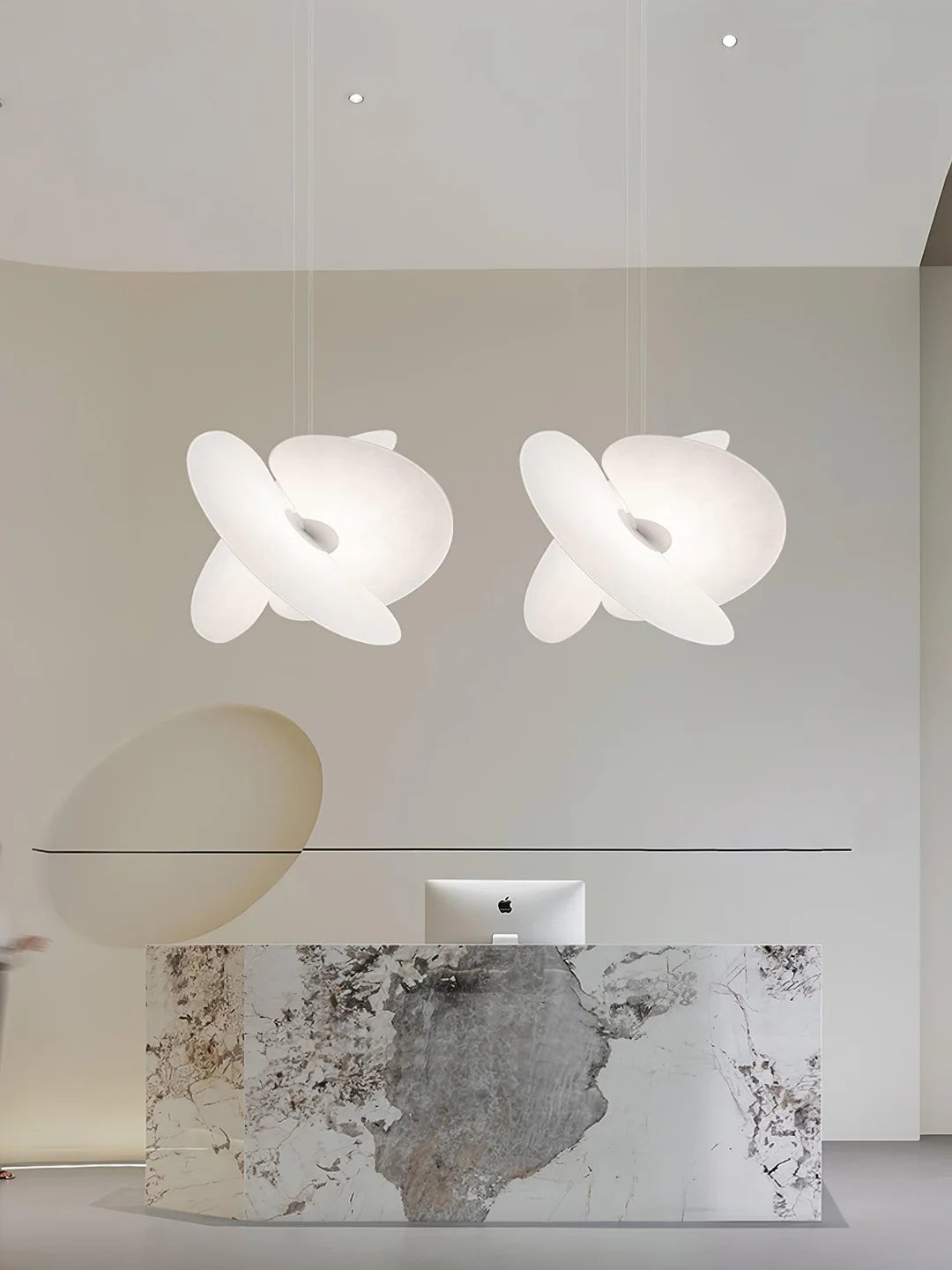 Modern pendant lights hanging above a desk with a marble surface.