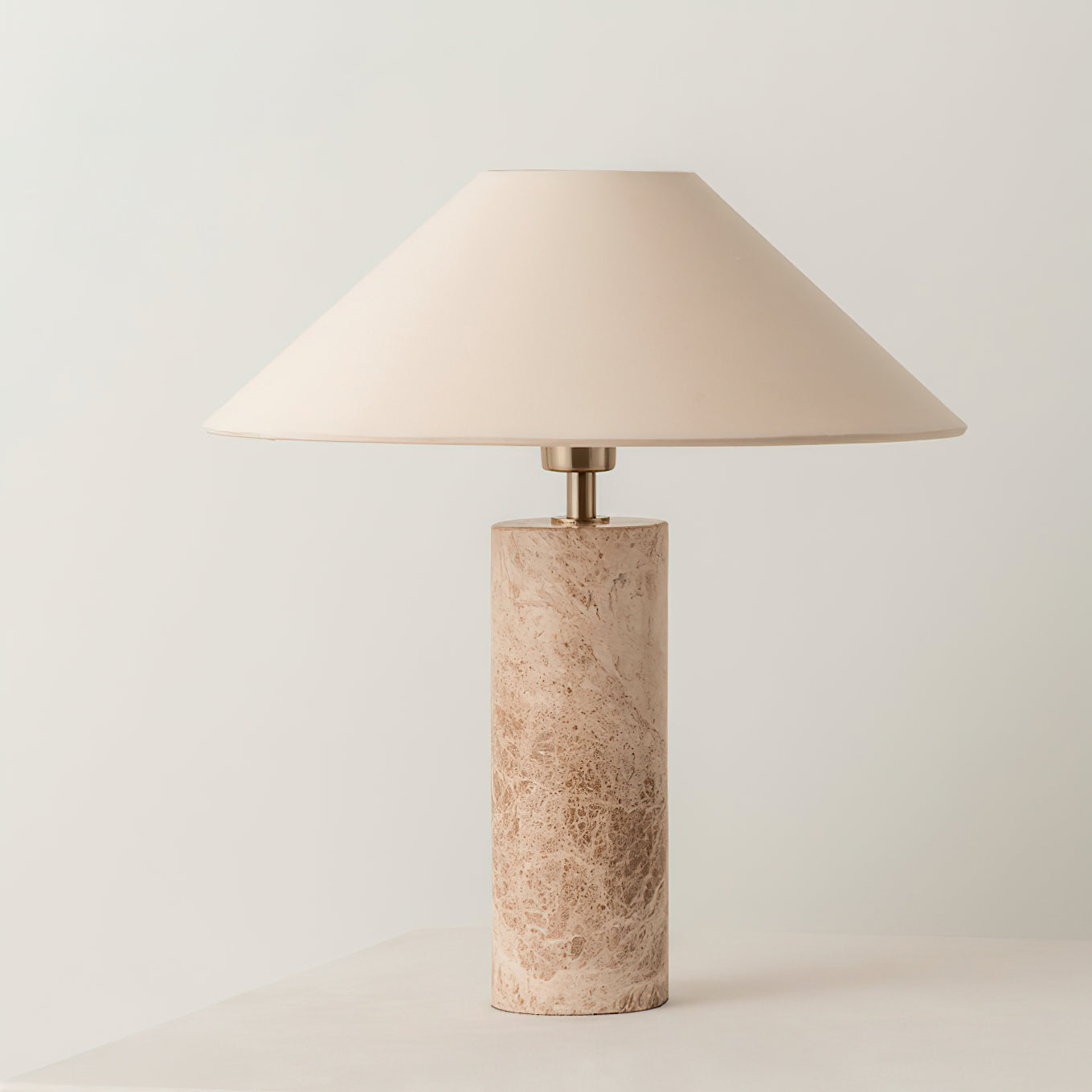 Table lamp with beige shade and cylindrical marble base on a light background