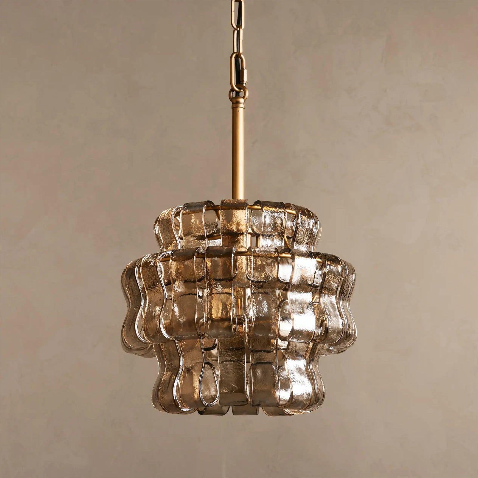 Decorative pendant light with glass shade and gold chain on a beige background