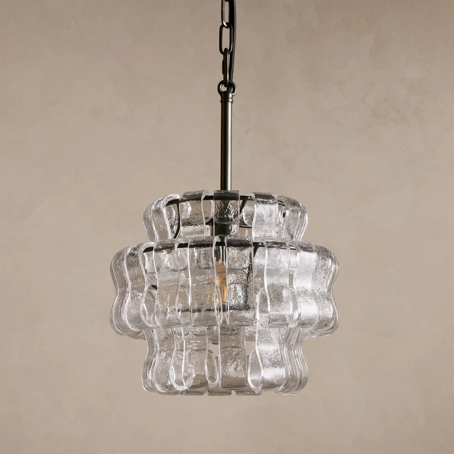 Clear glass pendant light with chain on a beige background