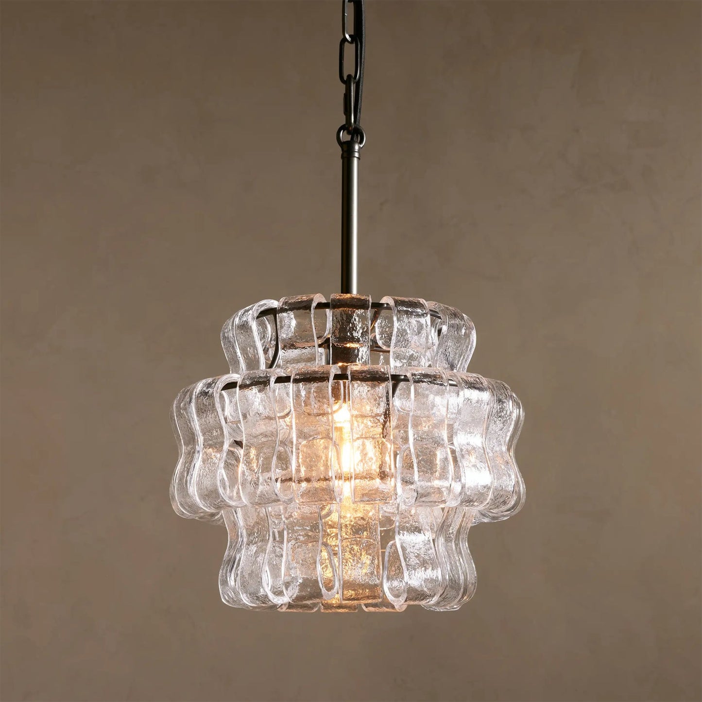 Clear glass pendant light with wavy design on a beige background