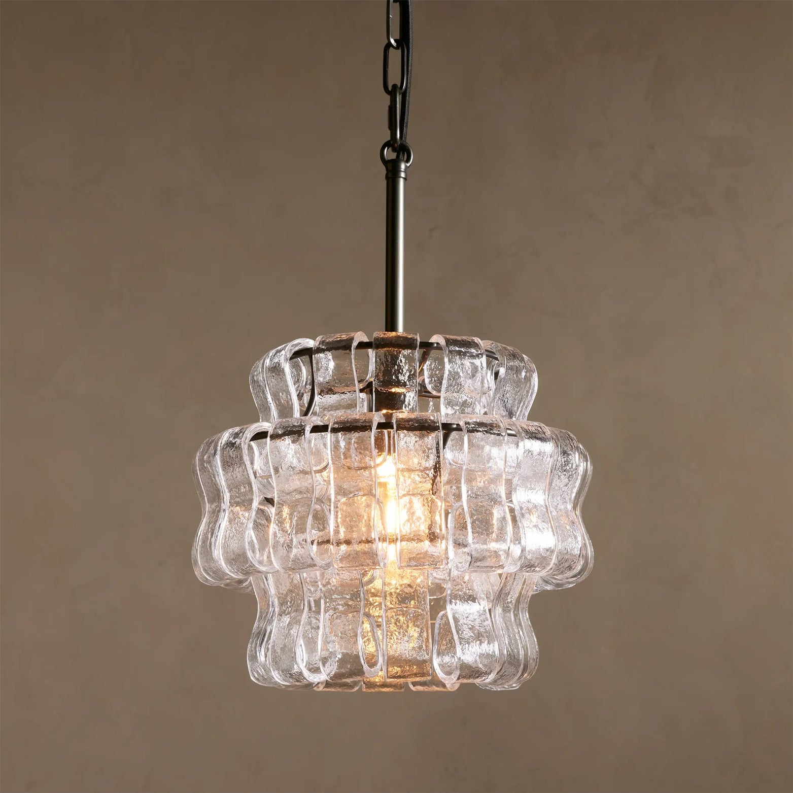 Clear glass pendant light with wavy design on a beige background