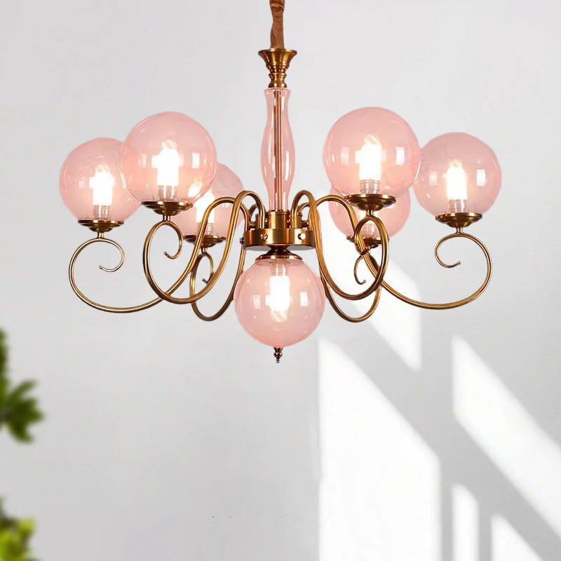 Yuri pink glass chandelier illuminated against a white wall