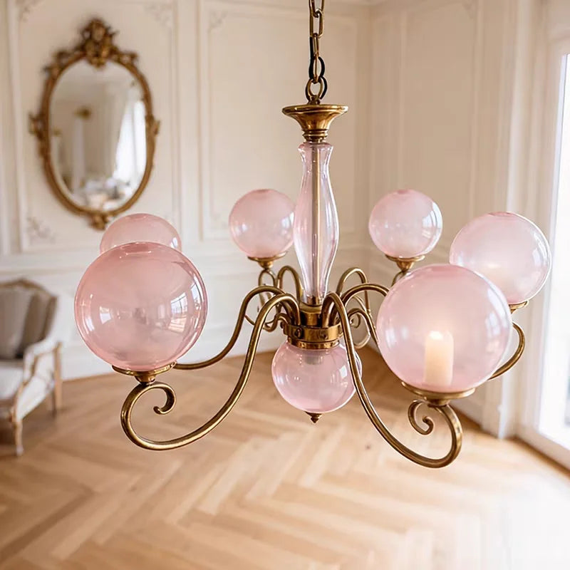 Yuri pink glass globe chandelier with curved gold-tone arms in a vintage-inspired room