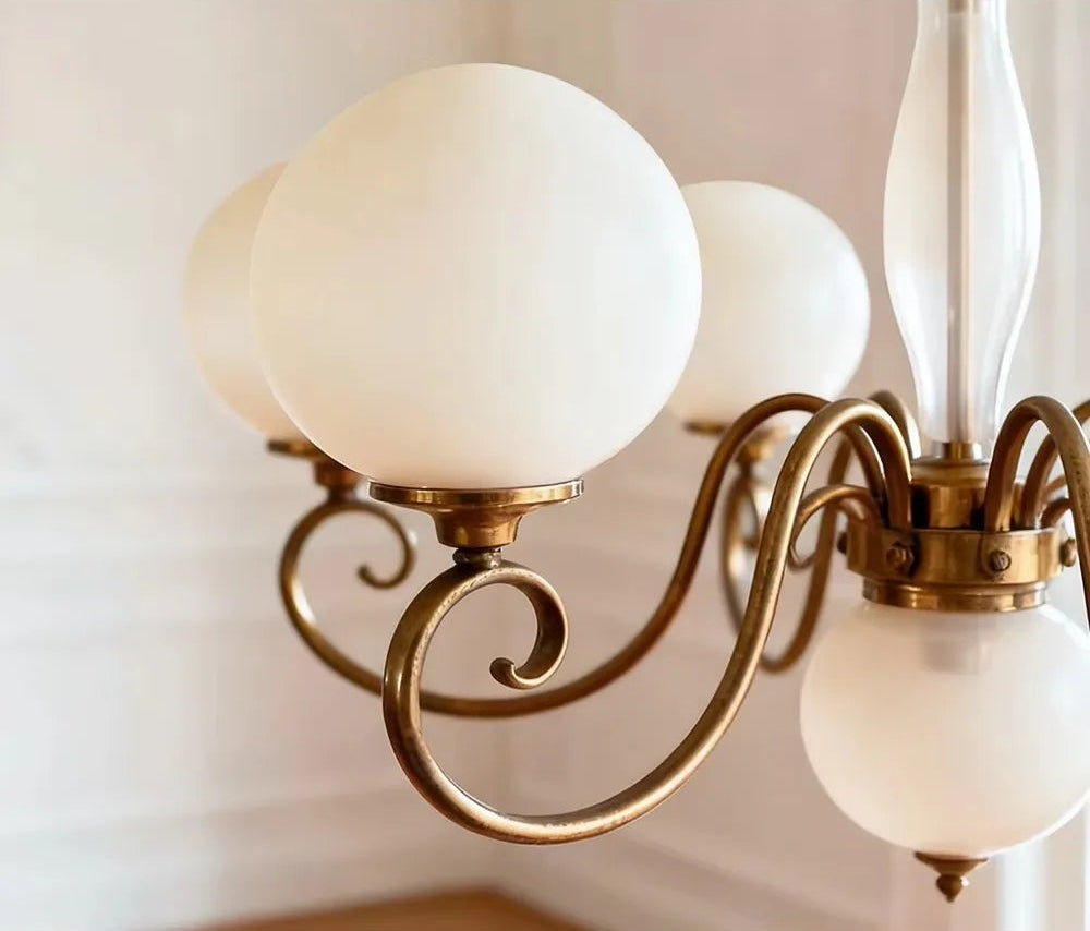 White glass globe shade and gold-tone arm on the Yuri Chandelier