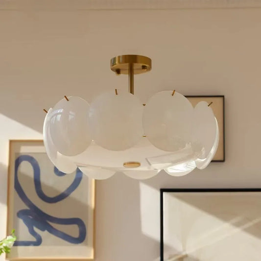 Modern ceiling light fixture with white glass shades in a room with framed artwork on the wall.