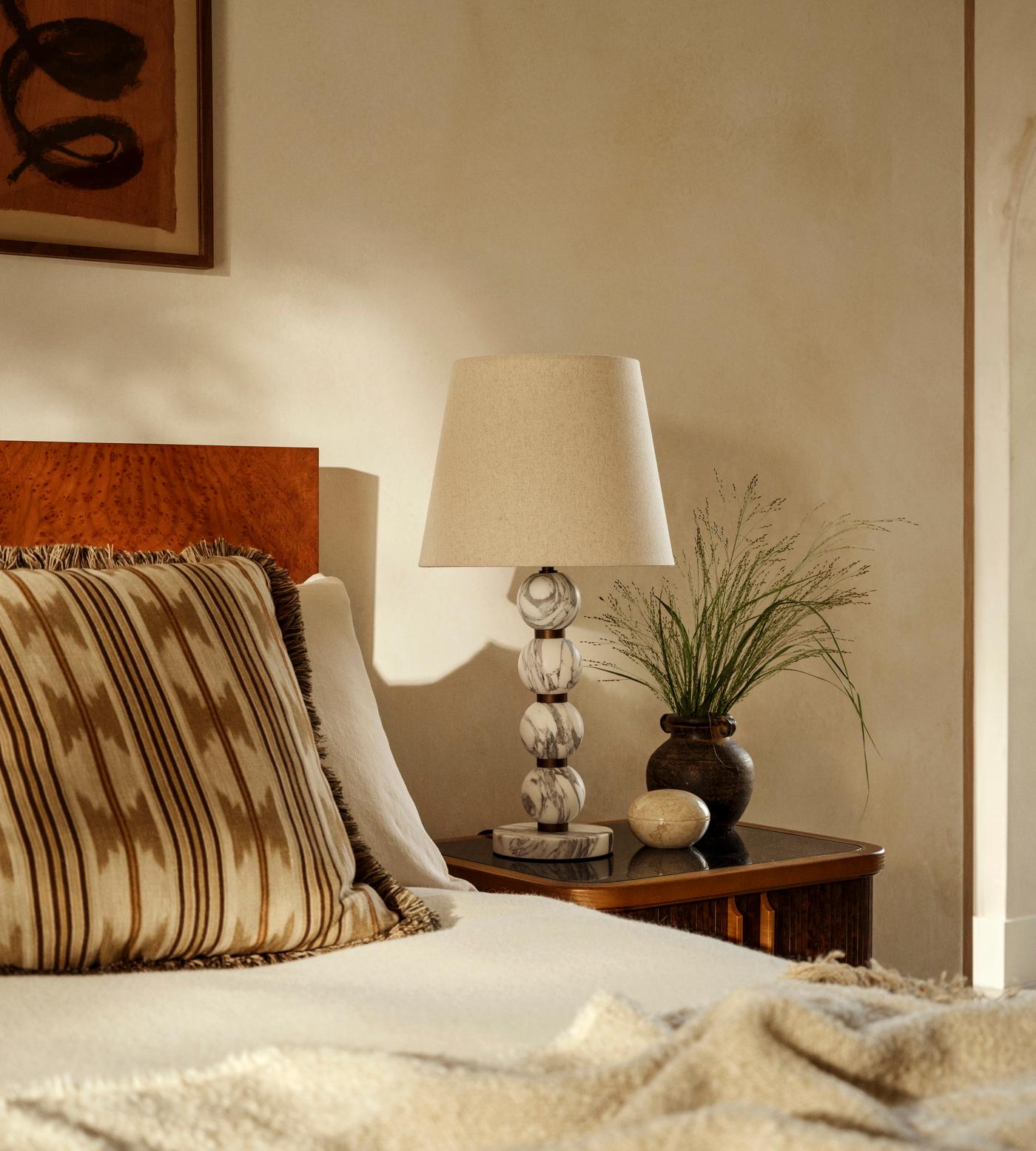 Bedroom with wooden headboard, lamp, and decorative items on a nightstand.