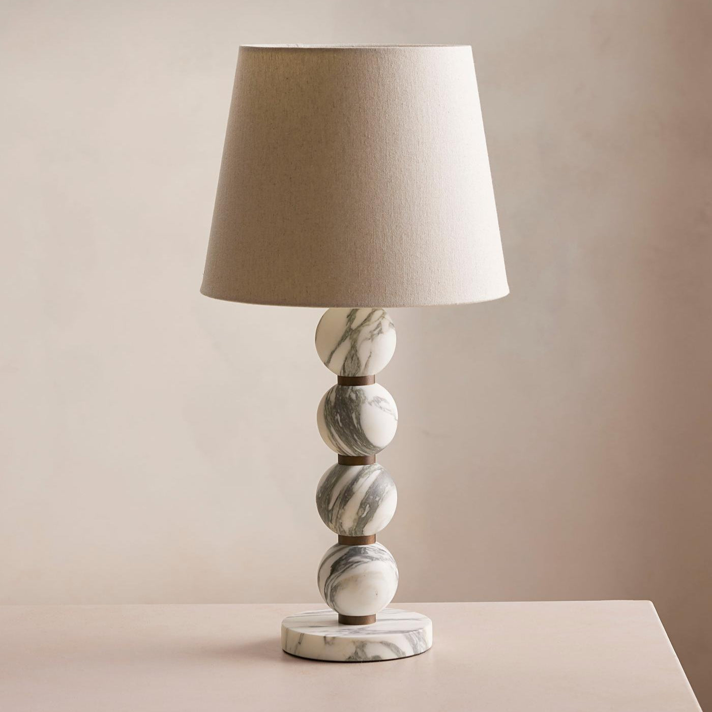 Table lamp with marble base and beige shade on a neutral background