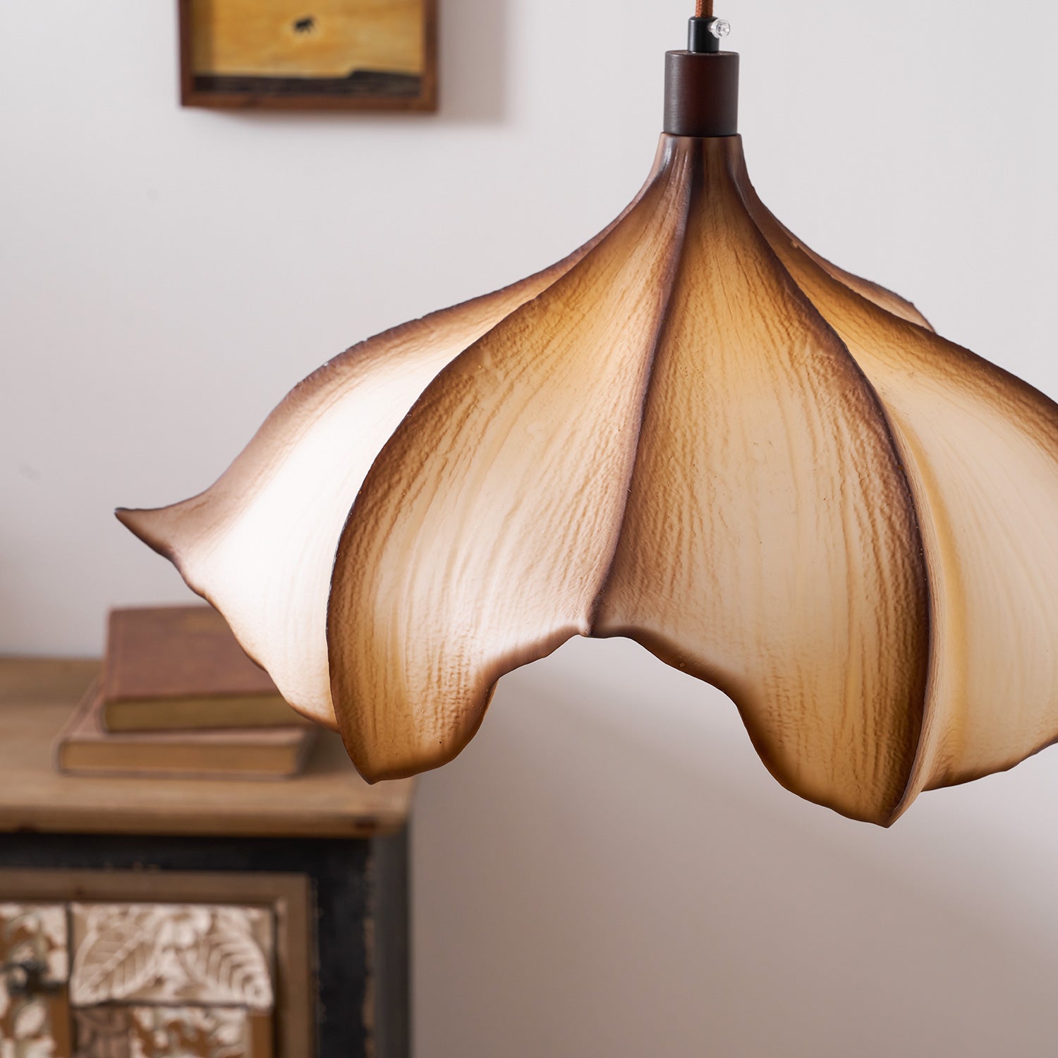 Floral-shaped pendant light with a warm glow in a softly blurred room setting.
