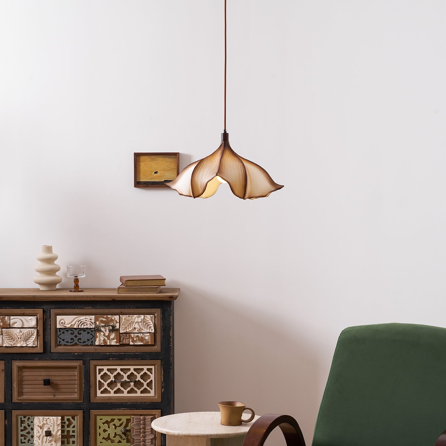 Decorative pendant light hanging above a wooden cabinet with a green chair and small table in a room.