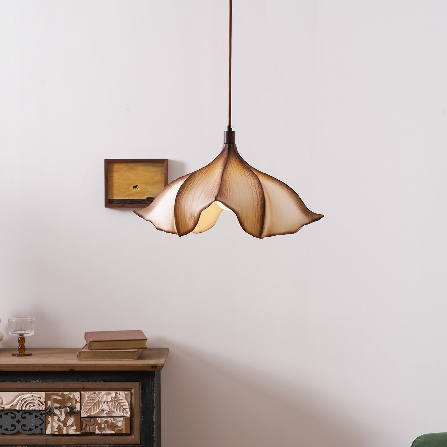 Decorative pendant light hanging above a wooden cabinet with a plain wall background
