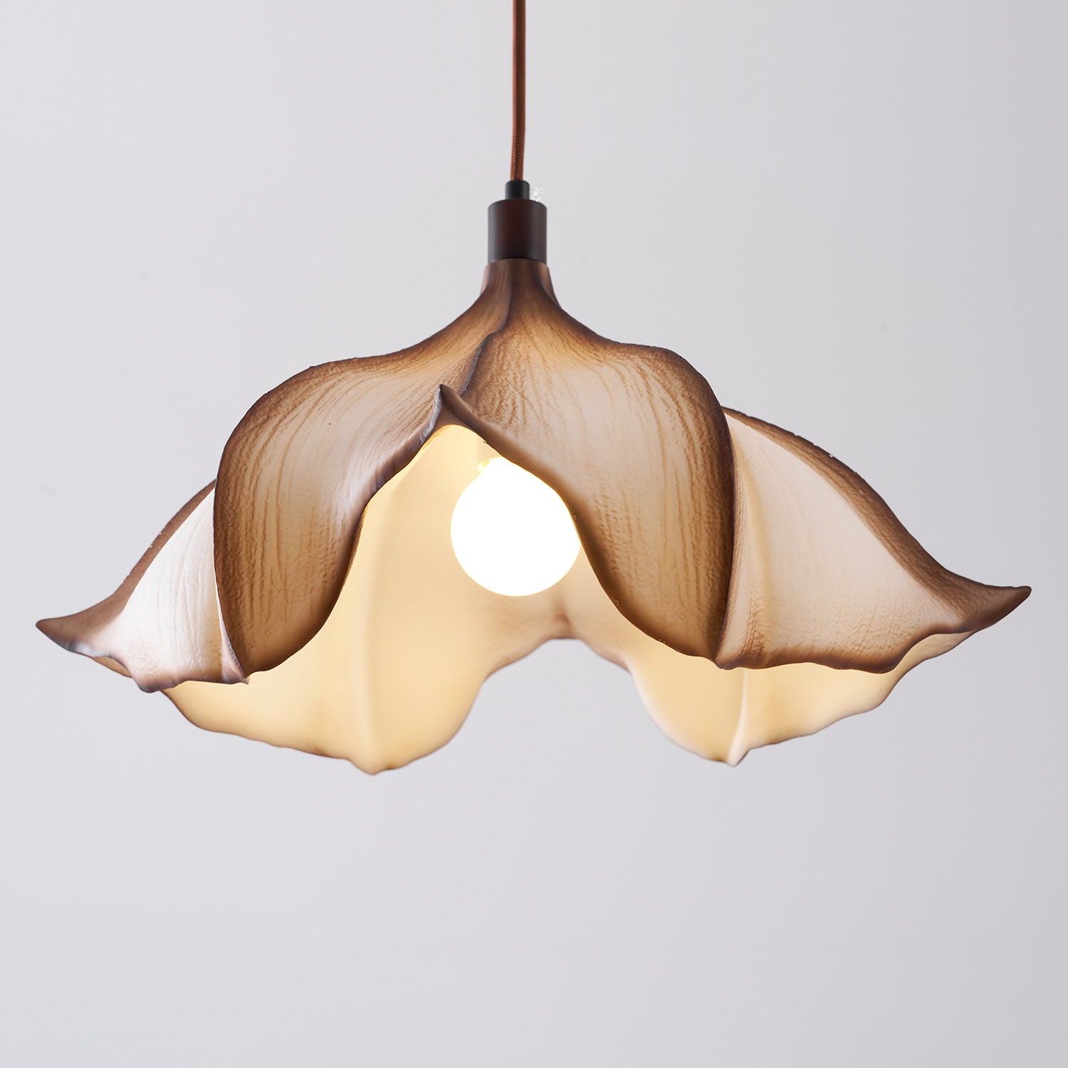 Floral-shaped pendant light with a soft glow on a plain background