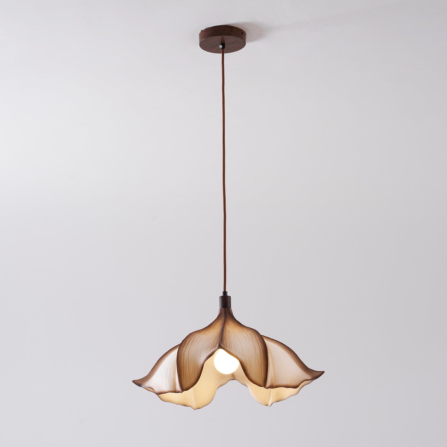 Floral-shaped pendant light with a brown glass shade on a plain background