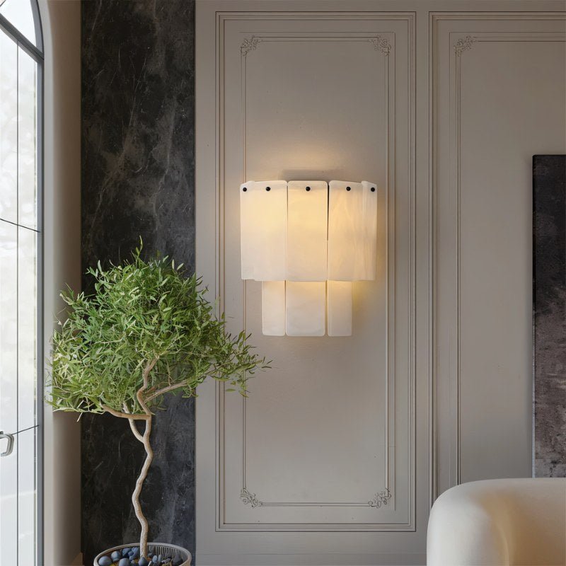 Wall-mounted light fixture on a decorative wall with a plant in the foreground