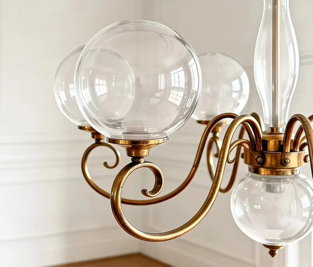 Clear glass globe shade and gold-tone arm on the Yuri Chandelier